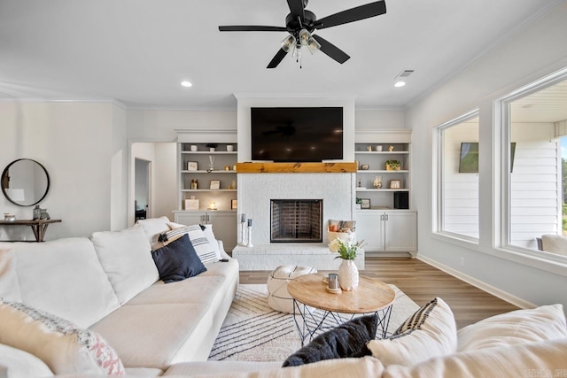 living room featuring crown molding, visible vents, wood finished floors, baseboards, and ceiling fan