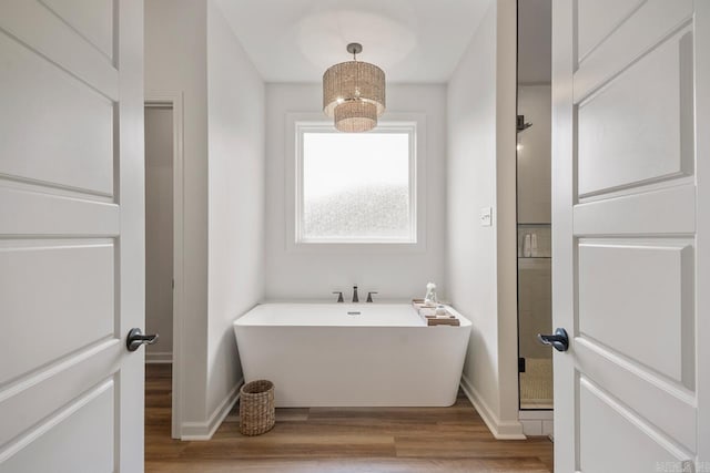 full bath with a freestanding tub, baseboards, a shower stall, and wood finished floors