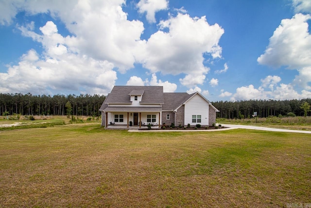 view of front of property with a porch, a view of trees, and a front yard