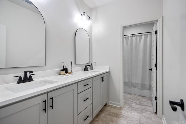 full bath with a sink, baseboards, double vanity, and visible vents