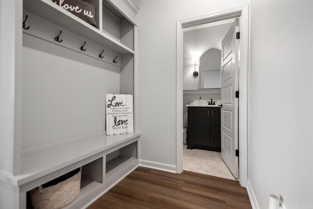 mudroom featuring baseboards, dark wood finished floors, and a sink