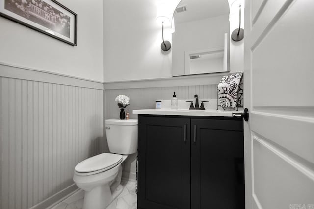 bathroom with visible vents, wainscoting, vanity, toilet, and marble finish floor