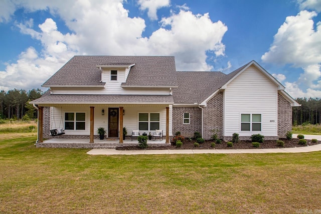 view of front of property featuring brick siding, a shingled roof, and a front yard