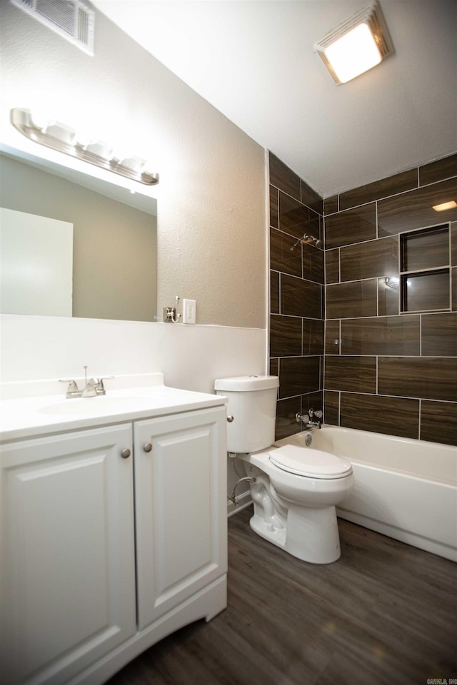 bathroom with visible vents, vanity, tub / shower combination, wood finished floors, and toilet