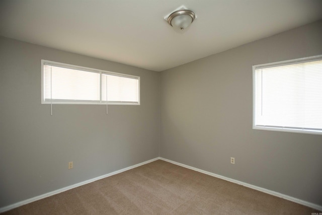 carpeted spare room featuring baseboards