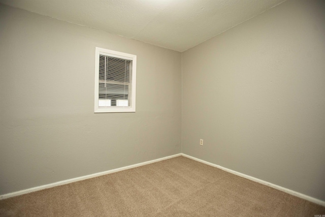 carpeted spare room featuring baseboards