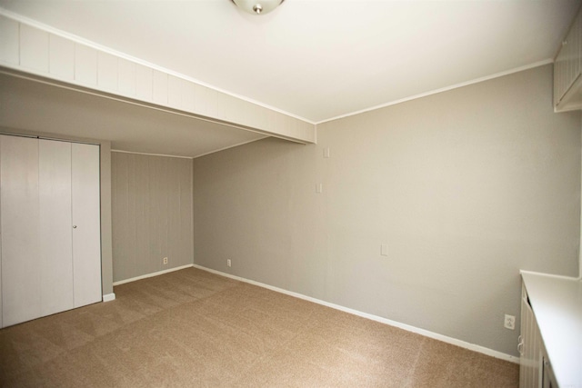 unfurnished bedroom with crown molding, baseboards, a closet, and light colored carpet