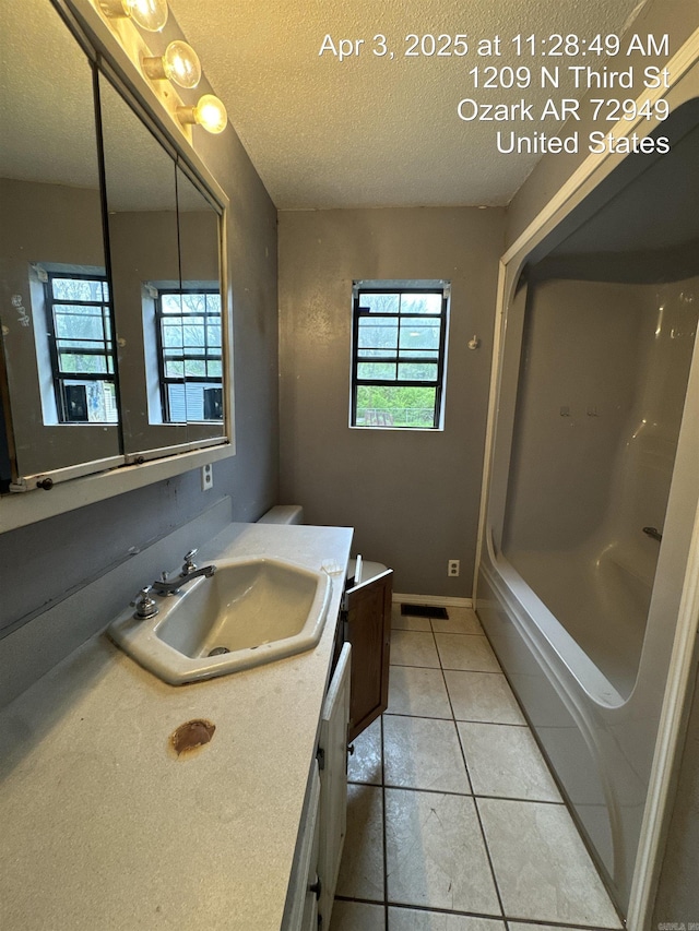 full bath featuring a tub, a textured ceiling, plenty of natural light, and vanity