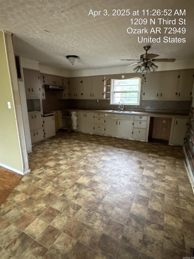 kitchen featuring cream cabinets, a sink, a ceiling fan, baseboards, and under cabinet range hood