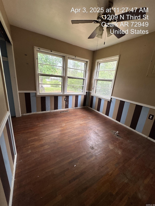 empty room with ceiling fan, wood finished floors, and visible vents