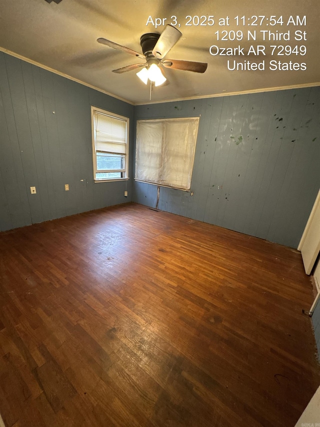 spare room featuring crown molding, wooden walls, ceiling fan, and wood finished floors