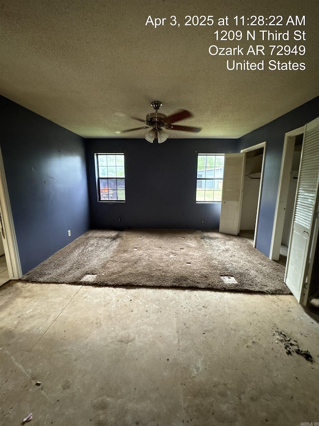 unfurnished bedroom with a textured ceiling, multiple closets, and multiple windows
