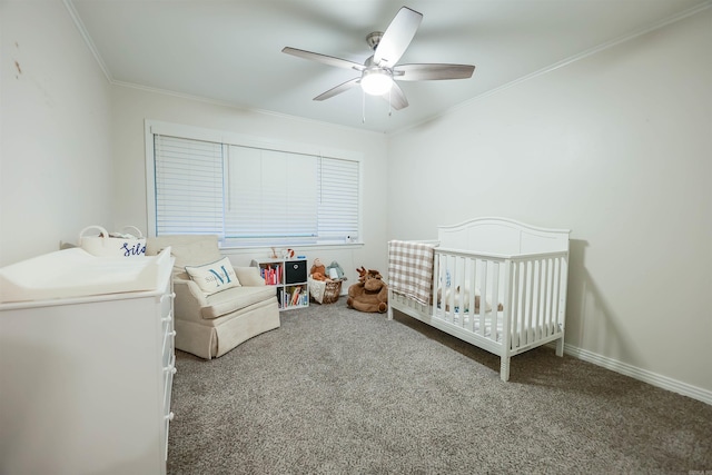 carpeted bedroom with crown molding, a nursery area, baseboards, and a ceiling fan
