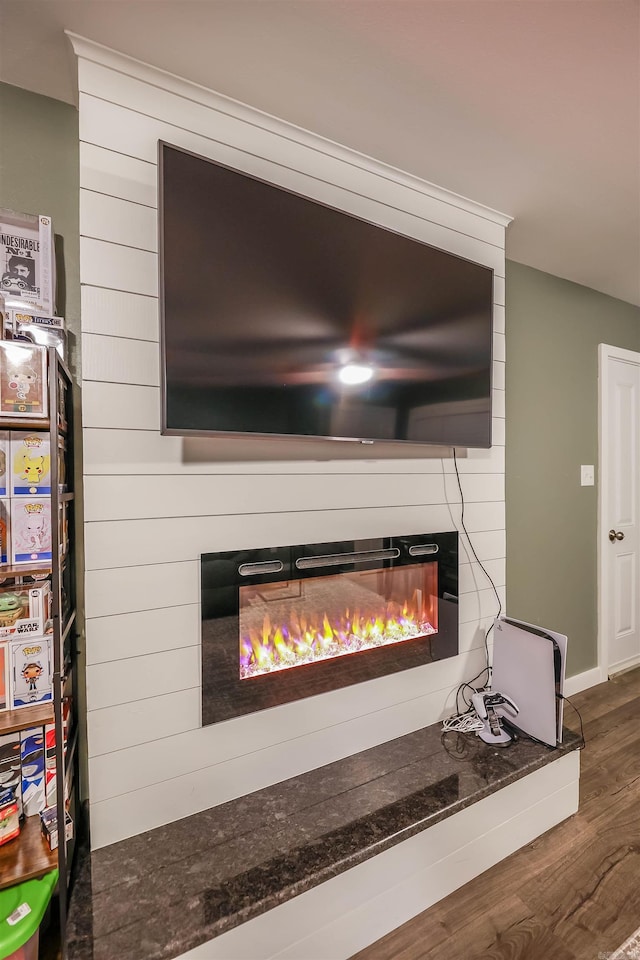 interior details with baseboards, a glass covered fireplace, and wood finished floors