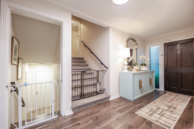foyer entrance featuring stairs, baseboards, ornamental molding, and wood finished floors