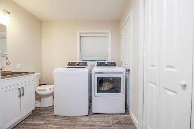 laundry room with a sink, laundry area, washing machine and dryer, and wood finish floors