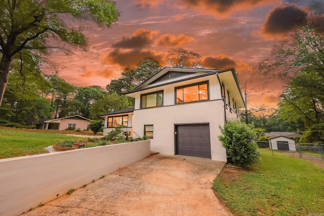 tri-level home with a lawn, an attached garage, fence, and driveway