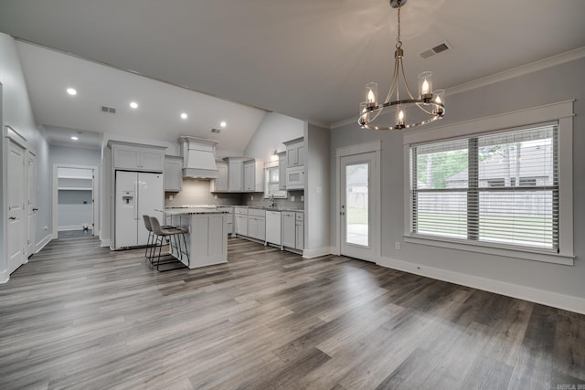 kitchen featuring visible vents, custom exhaust hood, white appliances, a chandelier, and a sink