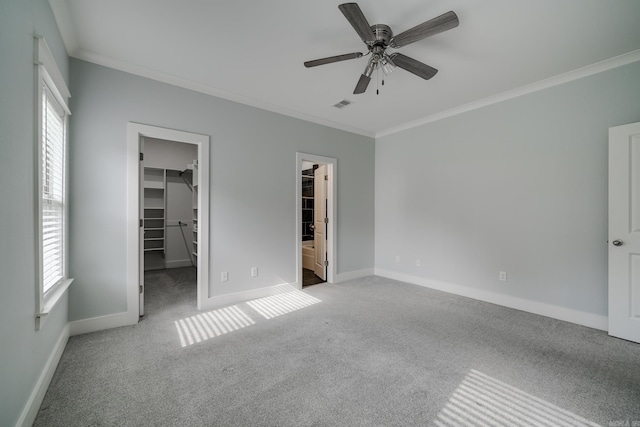 unfurnished bedroom featuring crown molding, carpet floors, a spacious closet, and visible vents