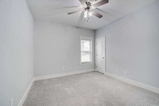 unfurnished room with baseboards, a ceiling fan, and light colored carpet