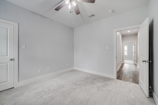 unfurnished room featuring carpet flooring, ceiling fan, visible vents, and baseboards