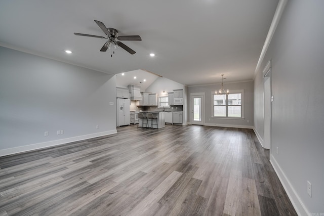unfurnished living room featuring crown molding, baseboards, dark wood-style floors, and ceiling fan with notable chandelier