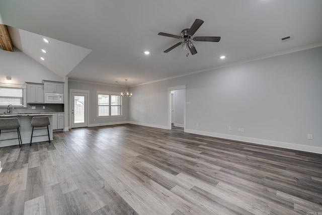 unfurnished living room featuring crown molding, ceiling fan with notable chandelier, recessed lighting, and a sink