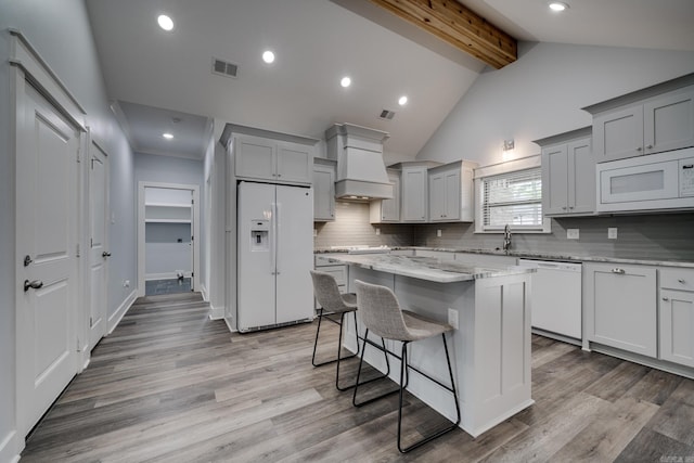 kitchen featuring visible vents, white appliances, a center island, tasteful backsplash, and custom range hood