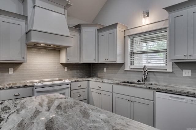 kitchen with lofted ceiling, white appliances, custom range hood, a sink, and backsplash