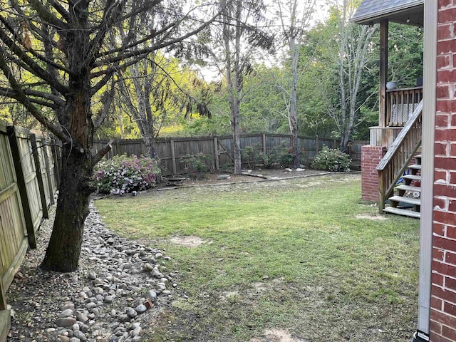 view of yard with a fenced backyard and stairway