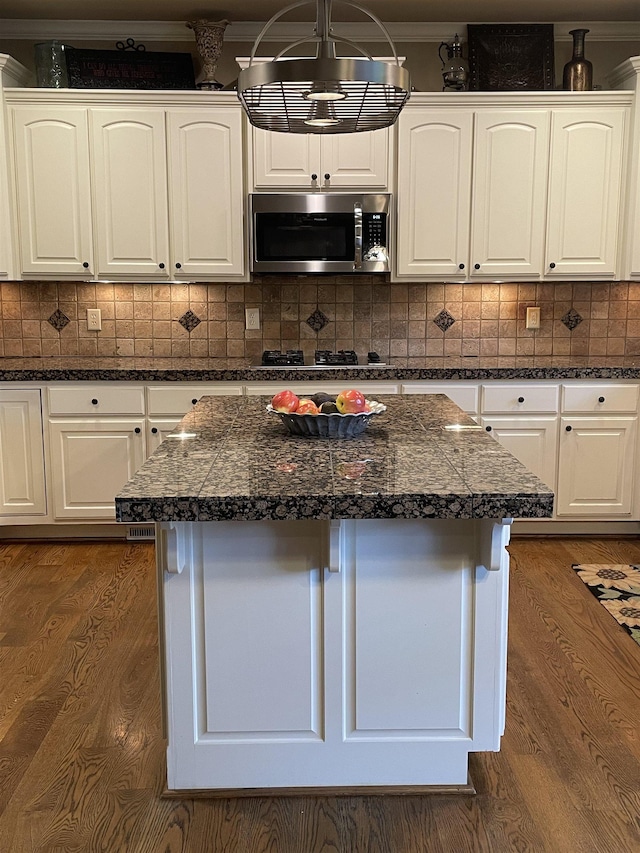 kitchen with a kitchen island, white cabinetry, and stainless steel microwave