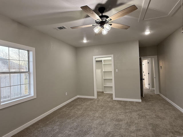 unfurnished bedroom featuring visible vents, a closet, baseboards, a walk in closet, and carpet flooring