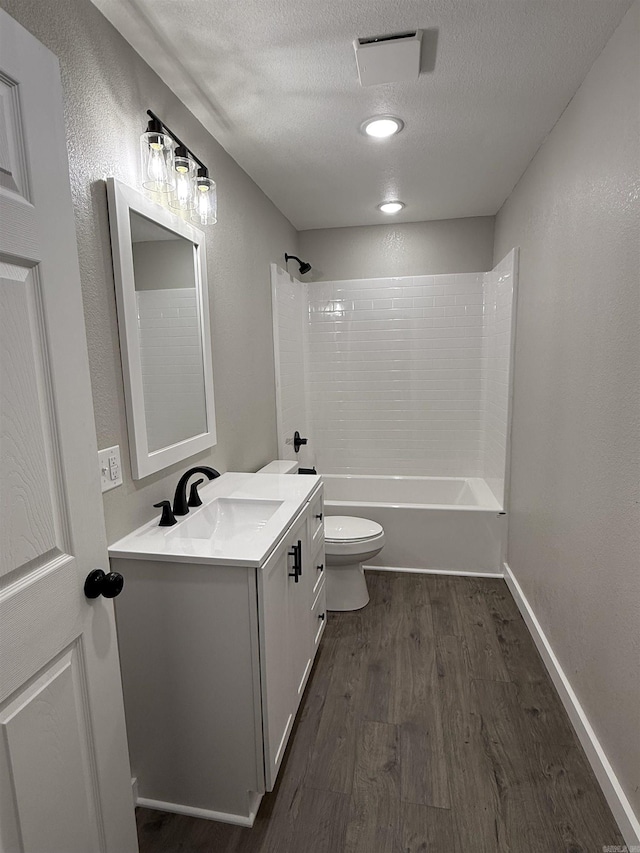 full bathroom featuring visible vents, vanity, wood finished floors, toilet, and a textured ceiling