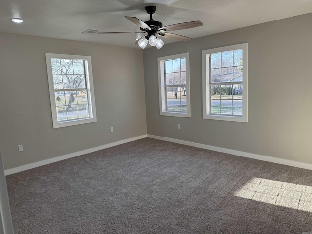 empty room with carpet floors, a ceiling fan, baseboards, and a wealth of natural light