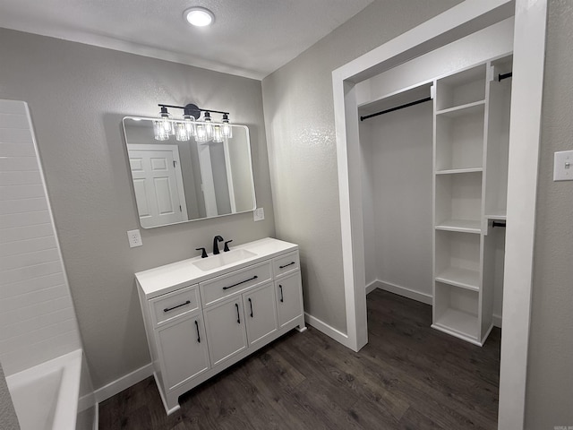 full bathroom featuring vanity, a bath, baseboards, and wood finished floors
