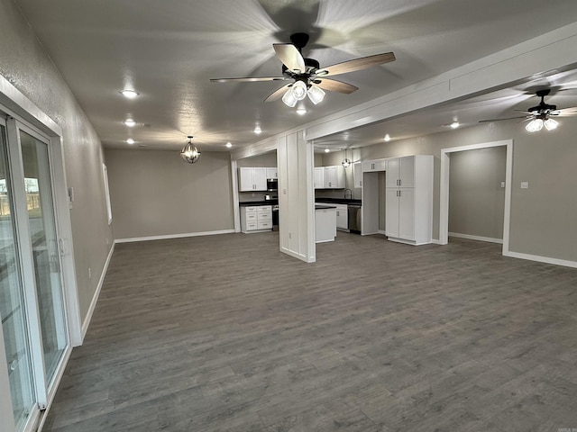 unfurnished living room featuring baseboards, a ceiling fan, and dark wood-style floors