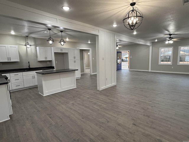 kitchen with open floor plan, dark countertops, and ceiling fan with notable chandelier