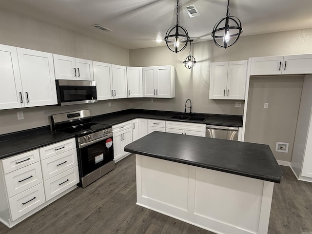 kitchen with dark countertops, appliances with stainless steel finishes, a sink, and visible vents