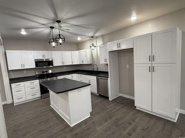 kitchen featuring dark countertops, appliances with stainless steel finishes, white cabinets, and a sink