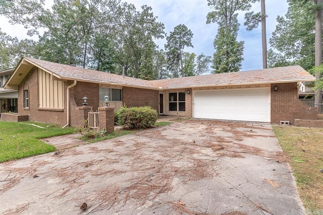 single story home with brick siding, board and batten siding, an attached garage, and driveway