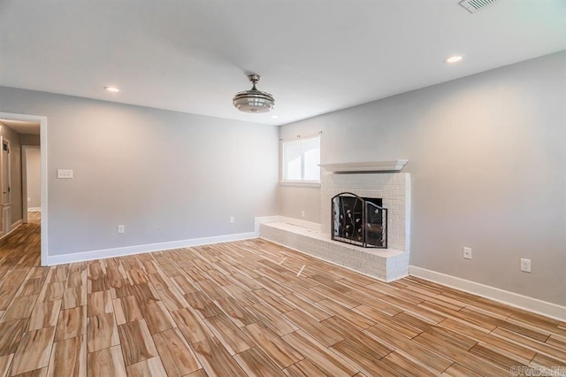 unfurnished living room with light wood-style floors, baseboards, a fireplace, and recessed lighting