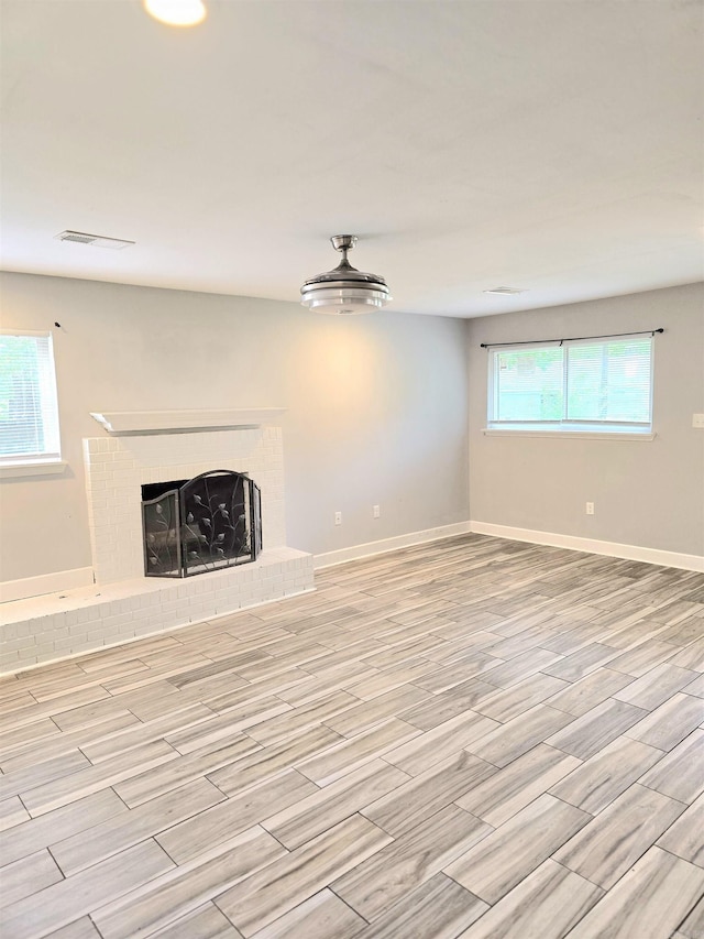 unfurnished living room featuring baseboards, visible vents, light wood finished floors, and a fireplace
