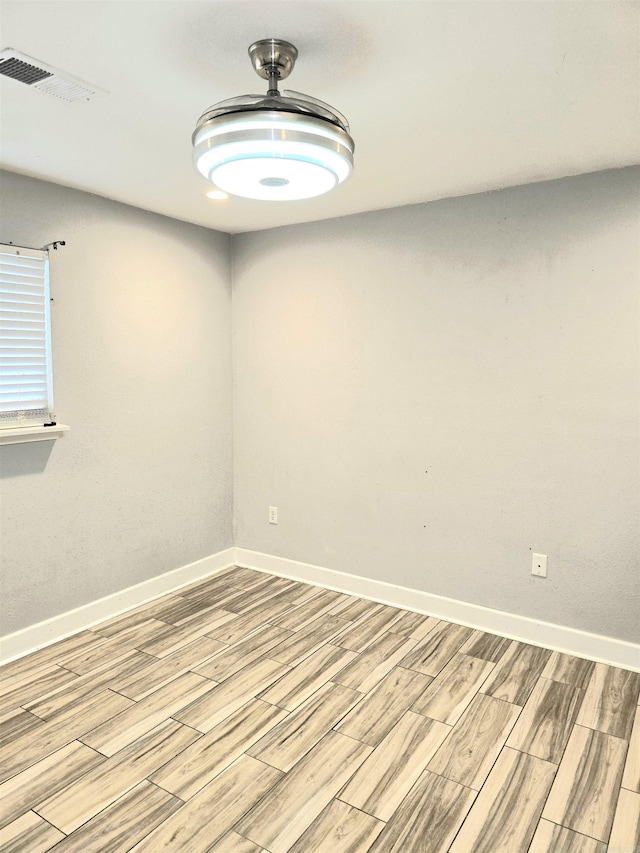 spare room featuring baseboards, light wood-style flooring, and visible vents