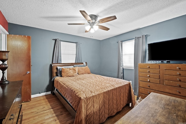 bedroom featuring a textured ceiling, baseboards, a ceiling fan, and wood finished floors