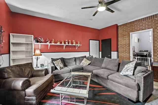 living room with ceiling fan and brick wall