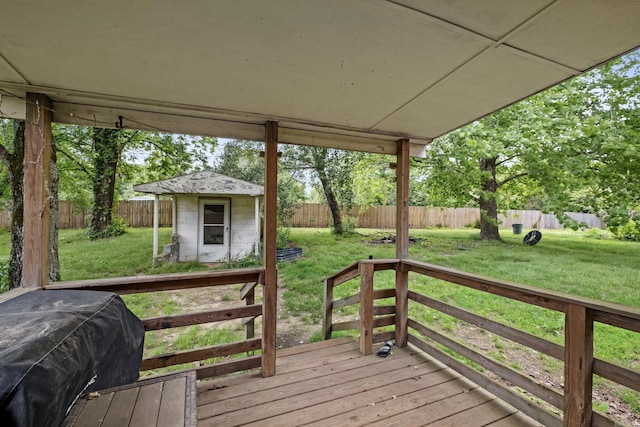 wooden deck featuring a yard, an outdoor structure, a fenced backyard, and a grill