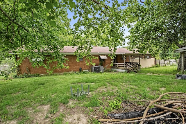 back of property featuring a yard, central AC, and brick siding