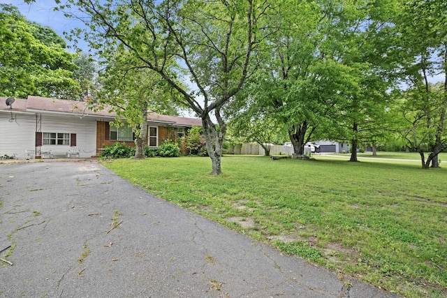 view of front facade featuring fence, driveway, and a front yard