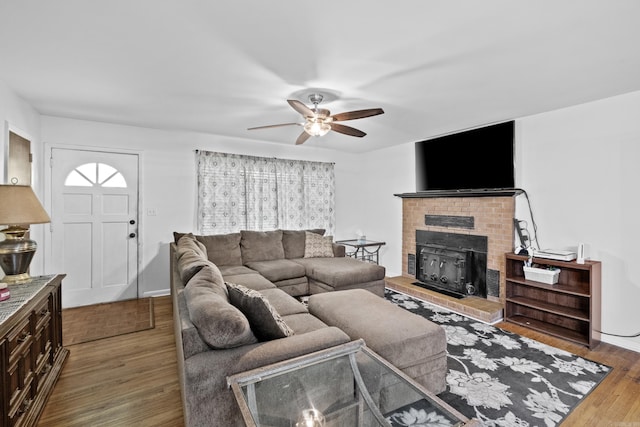 living area featuring a ceiling fan, wood finished floors, and a fireplace