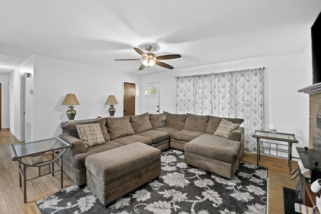 living area featuring a ceiling fan, wood finished floors, and a fireplace